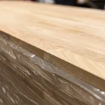 Close-up of the 20 mm edge and thickness of the finger-jointed oak furniture panel in packaging.