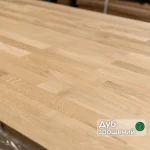Close-up of a finger-jointed oak furniture board with a text overlay indicating the wood species.