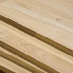 Close-up of the edges and finger-joint patterns of stacked oak furniture boards.