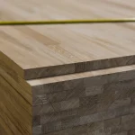 Close-up of the corner of stacked oak panels showing the finger-jointed structure and a yellow tape measure.