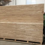 Pallet of shrink-wrapped 20mm oak furniture panels in a warehouse.