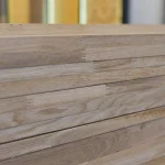 Close-up of the finger-joint connection on the edges of stacked oak furniture panels.