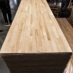 Stack of finger-jointed oak furniture boards in a warehouse.