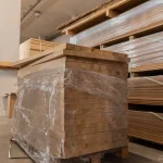 Large pallet of wrapped finger-jointed oak furniture boards in a warehouse.