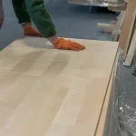Worker inspecting the smooth surface of a finger-jointed alder furniture board.