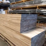Stack of finger-jointed ash furniture panels on a pallet in an industrial warehouse setting.