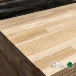 Close-up of a 40mm finger-jointed ash furniture panel stack showing the sandwich structure and wood grain.