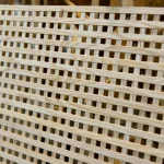 Текстура світлої деревини ясеня на декоративній решітці з квадратними отворами