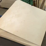 A sheet of 12 mm FC birch plywood, grade B/BB, held by a worker in the warehouse