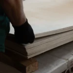 Gloved hand lifting the edge of an FC birch plywood sheet