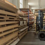 Склад компанії WoodWay Expert з палетами гнучкої фанери та автонавантажувачем.