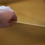 Рука тримає тонкий край листа фанери окуме, крупний план