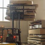 Forklift moving a pallet of veneered plywood in the WoodWay Expert warehouse.