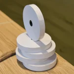 Vertical stack of white gummed veneer tape rolls on a wooden table