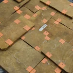 Multiple bundles of Myrtle root veneer sheets laid out on a flat surface.