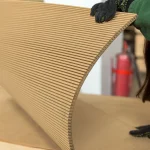 A person in gloves holds a bent sheet of flexible MDF 10 mm