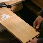 Worker holding a sheet of sawn cherry veneer in the warehouse