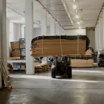 Forklift transporting a large pallet of sliced Anegre veneer in the warehouse