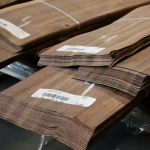 Edges of 0.6 mm sliced American Walnut veneer sheets with barcode labels