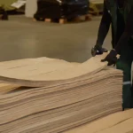 Process of selecting and sorting packs of natural sliced pine veneer by a warehouse worker.