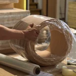 Packing a roll of sliced elm veneer in protective stretch wrap