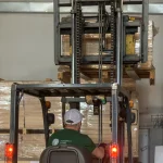 Forklift moving a pallet of wood materials in the warehouse