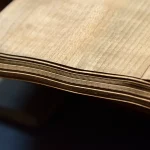 Edge view of a bundle of sliced cherry veneer sheets showing 0.6 mm thickness.