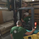 WoodWay Expert warehouse: workers in branded t-shirts loading veneer using a forklift.