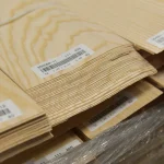 Sheet edges in a pack of sliced white ash veneer showing 0.6 mm thickness