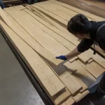 Warehouse worker showing a sheet of sliced white ash veneer.