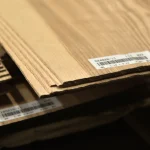 Edge view of sliced olive ash veneer sheets showing 2.5 mm thickness