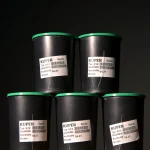Five black spools of Kuper K12 glue thread stacked in a pyramid on a dark background