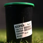 Vertical close-up of Kuper K12 glue thread spool against grass background