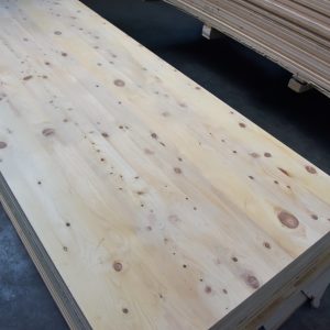 Full American pine wall panel with dense round knots, on a stack near other bundles.