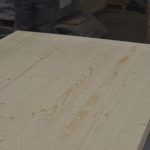 Поверхня зрощеного щита із сосни з сучками та торцем стосу поруч